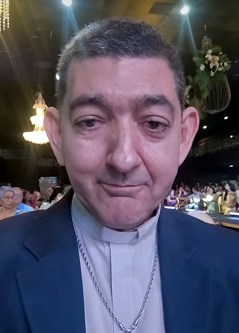 Padre Aderso de clergyman e crucifixo, em um encontro com a comunidade